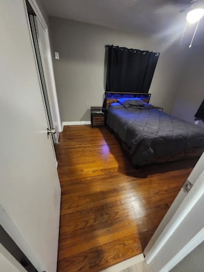 A bedroom with a bed, a nightstand, and a wooden floor. - Family retreat home (Jacksonville)