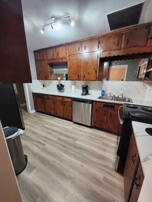 A kitchen with wooden cabinets, a stainless steel dishwasher, a stove, and a microwave. - Family retreat home (Jacksonville)