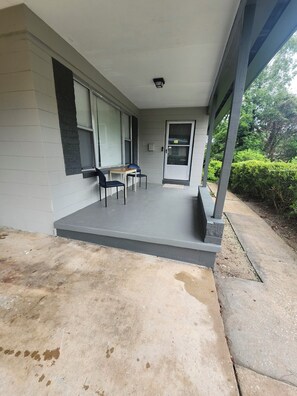 A covered outdoor area with a concrete floor, a table with chairs, and a door. - Family retreat home (Jacksonville)