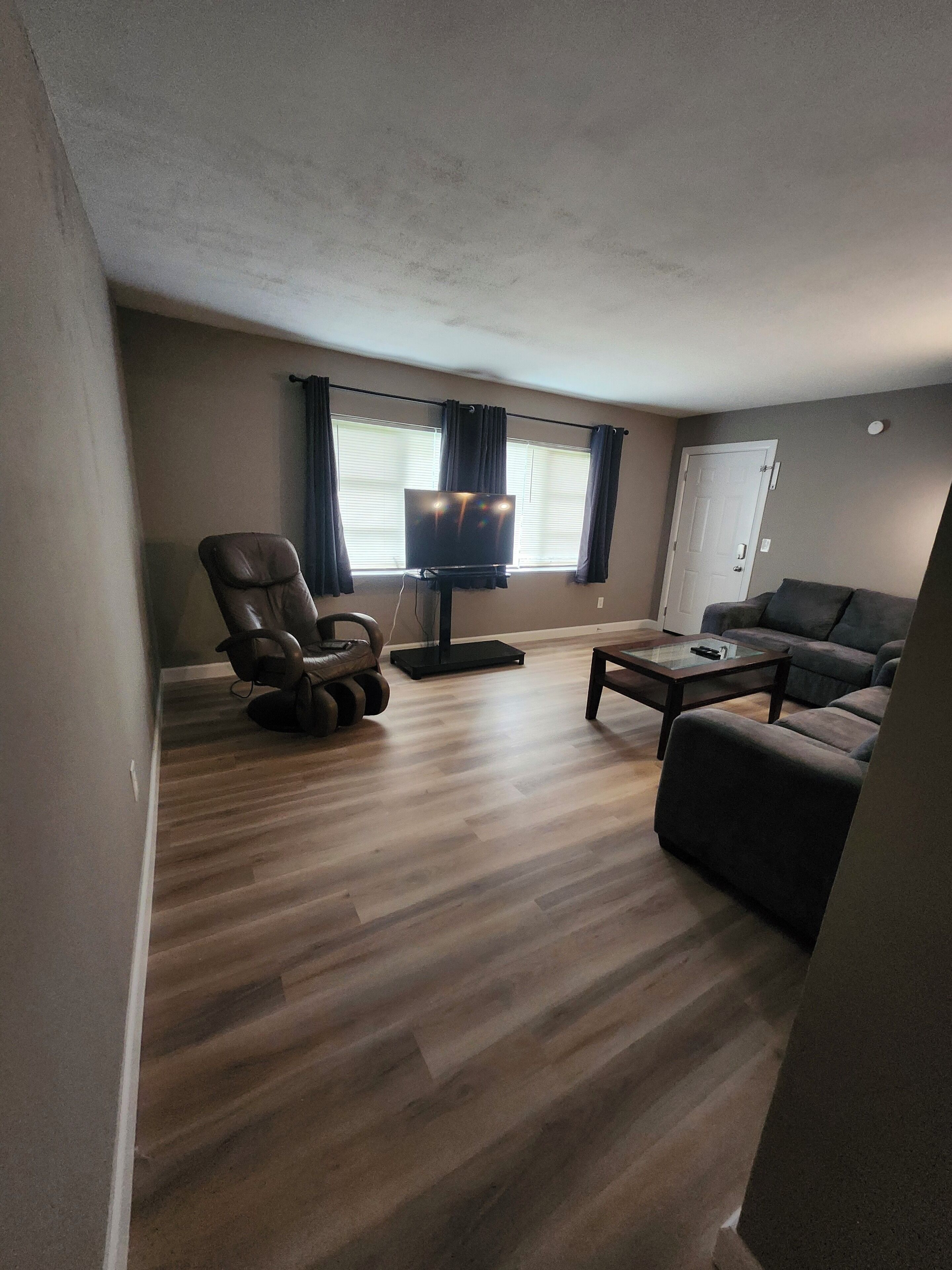 Un salon avec un fauteuil en cuir, un canapé, une table basse et un téléviseur posé sur un meuble.