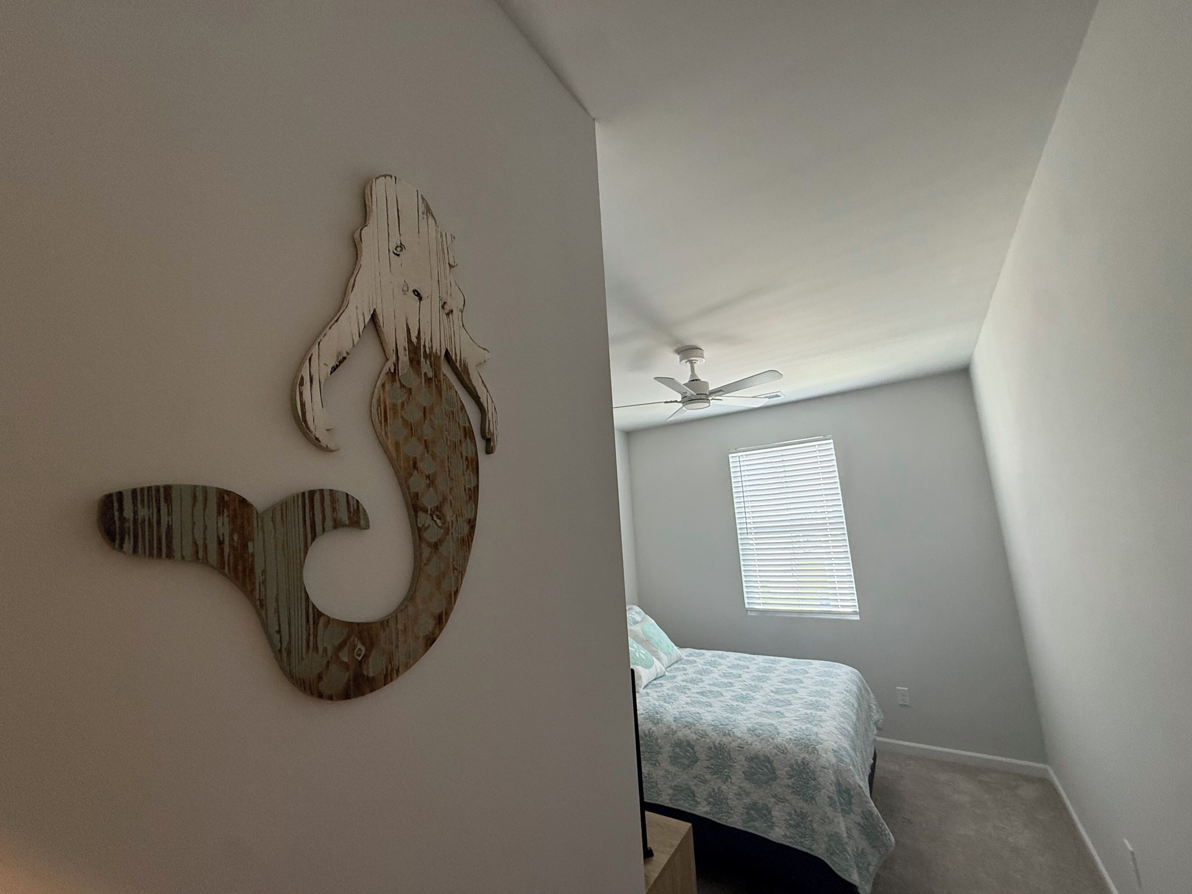 A bedroom with a bed, a ceiling fan, and a window with blinds.