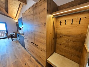 A modern kitchen with wooden cabinetry, a built-in bench, and a dining area with chairs and a table. - Penthouse Studio II with a balcony, fantastic view, and parking space (Bruck an der Großglocknerstraße)