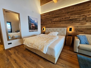 Ein Schlafzimmer mit einem großen Bett, einem Spiegel, einer Holzwand und einem kleinen Sofa.