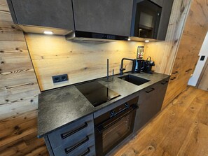 Een moderne keuken met een ingebouwde oven, een spoelbak en een koffieapparaat.