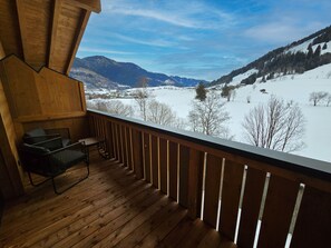 Een houten terras met uitzicht op een besneeuwd landschap en bergen.