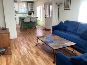 A living room with a blue sofa, a coffee table, and a wooden floor. - Stacy’s 2nd st cottages front house (Ashland)