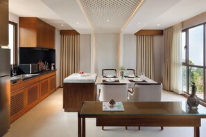 A modern kitchen with a dining area, large windows, and a view of the outdoors. - Dusit Thani Himalayan Resort (Dhulikhel)