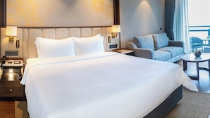 Et hotelværelse med en stor seng, en sofa, et lille bord og udsigt over byen.