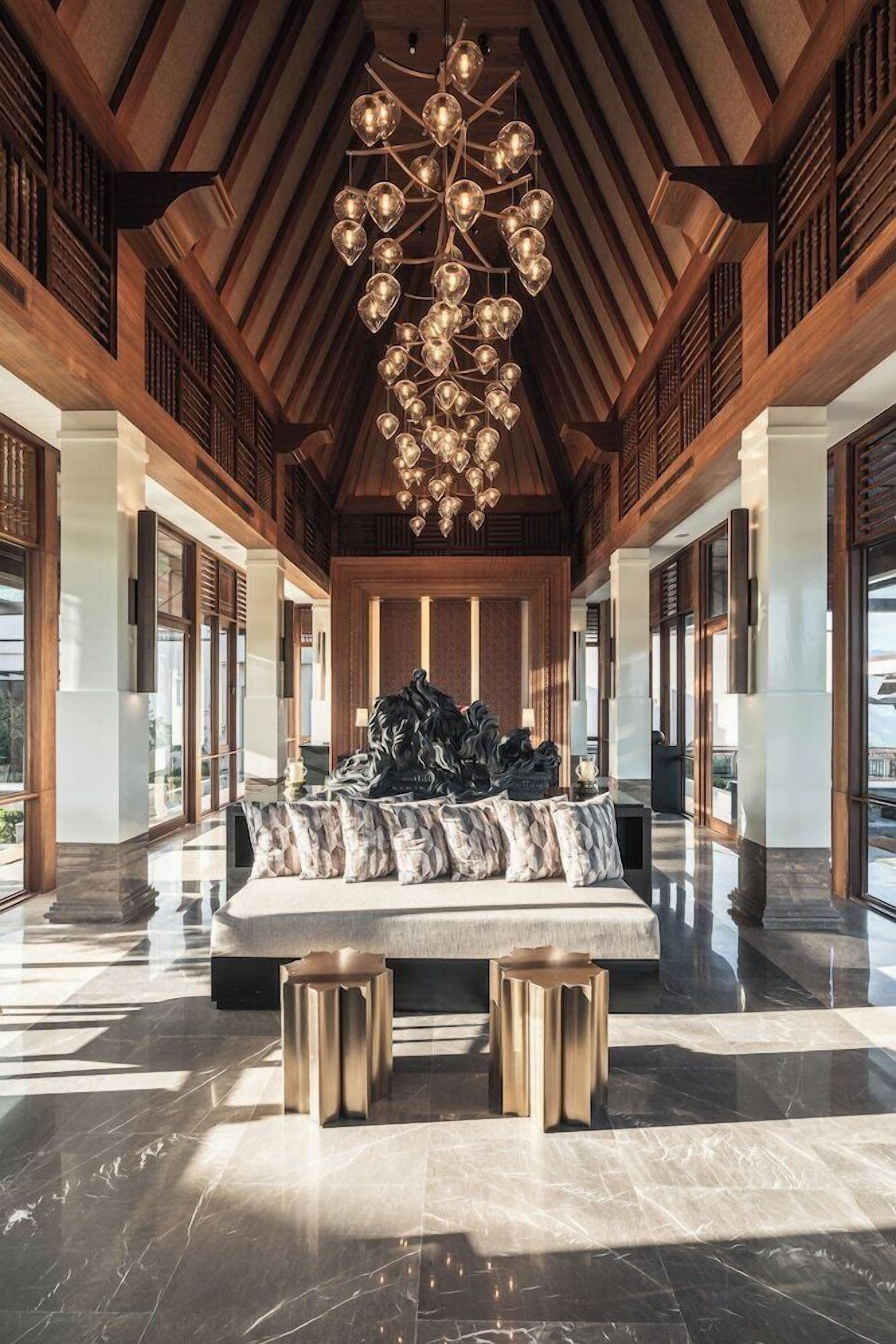 A spacious lobby with a high ceiling, a central seating area, and a modern chandelier.