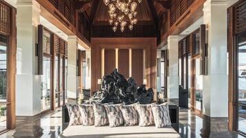 A spacious lobby with a high ceiling, a central seating area, and a modern chandelier.