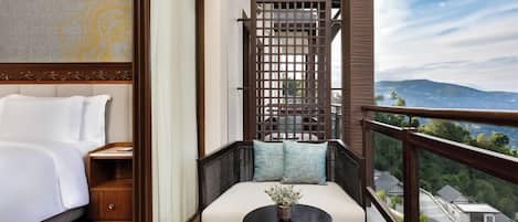 A balcony with a bed, a sofa, and a small table with a vase.