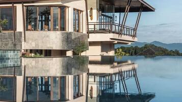 A modern building with a reflective pool, large windows, and a balcony.