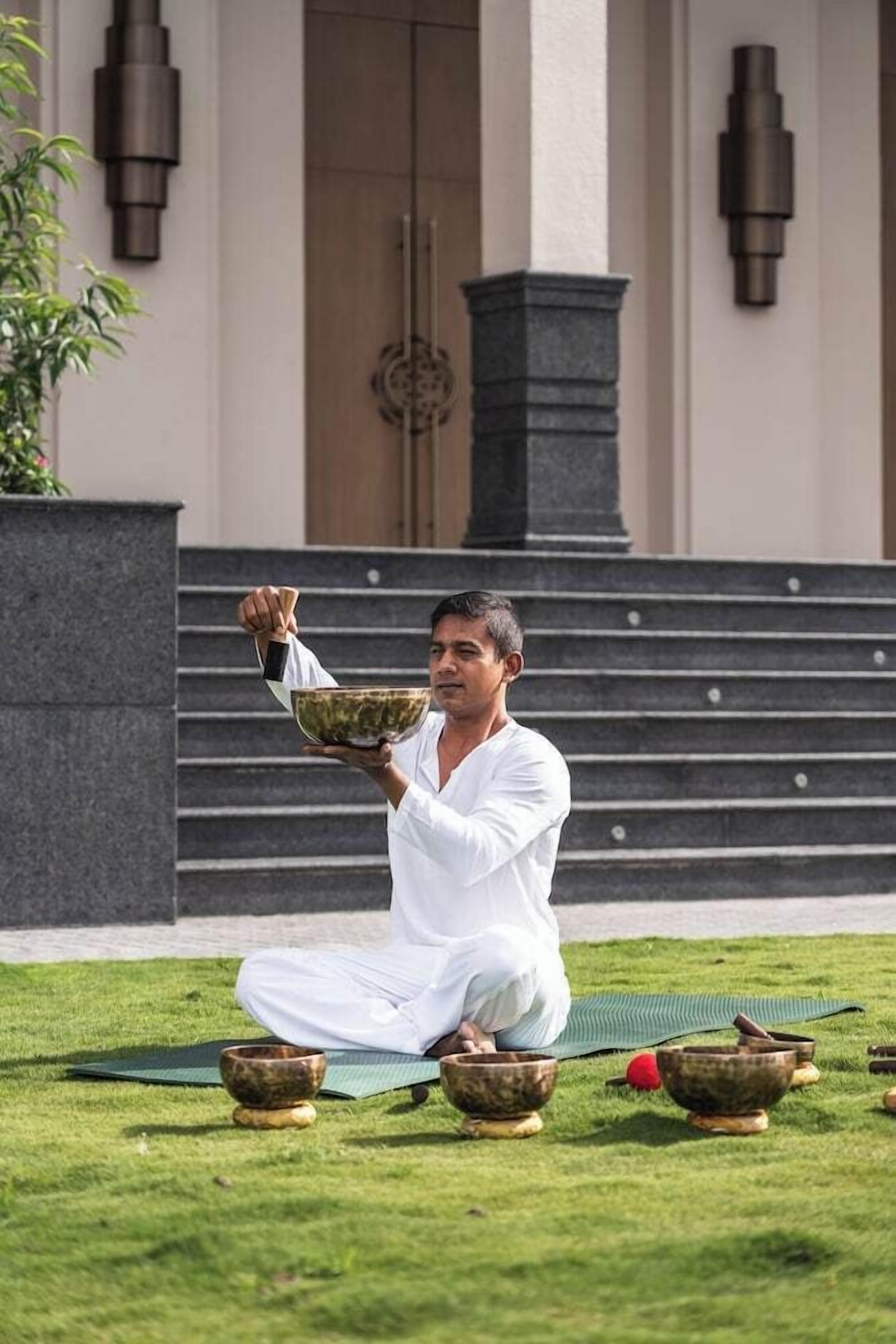 A person sitting on a mat outdoors with bowls in front of them.