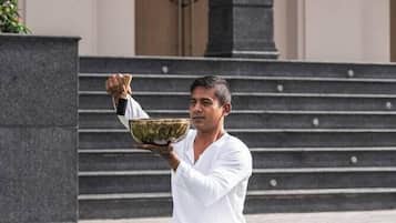 A person sitting on a mat outdoors with bowls in front of them.