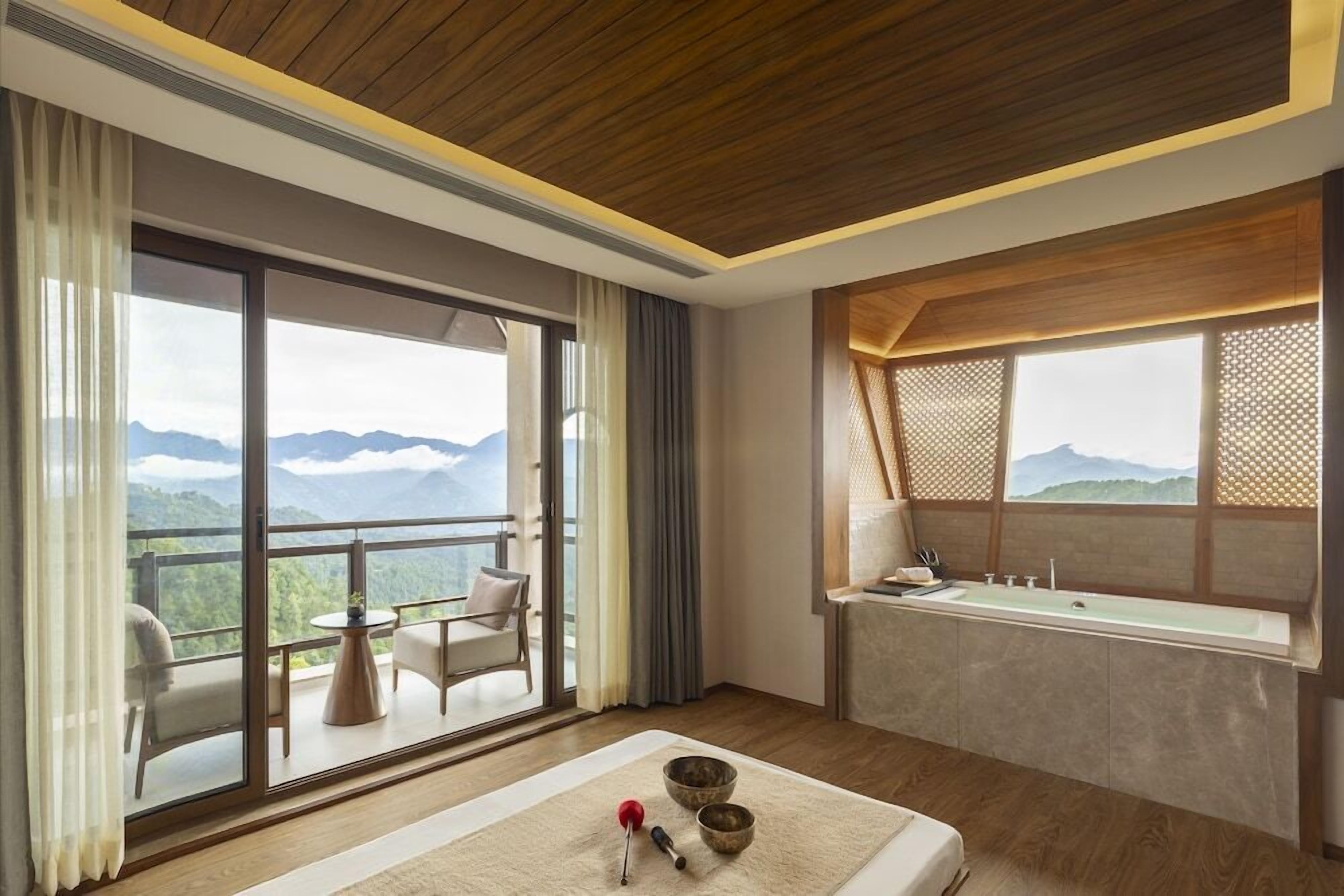 Una habitación de hotel moderna con balcón, un ventanal grande y un baño.