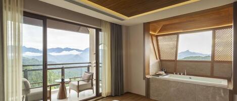 A modern hotel room with a balcony, a large window, and a bathroom.
