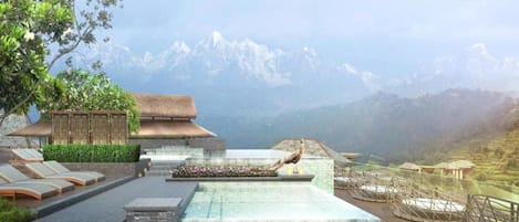 Un complexe hôtelier doté d’une piscine, de chaises longues et offrant une vue sur les montagnes.
