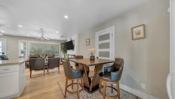 A modern kitchen with a dining area, wooden flooring, and a ceiling fan.
