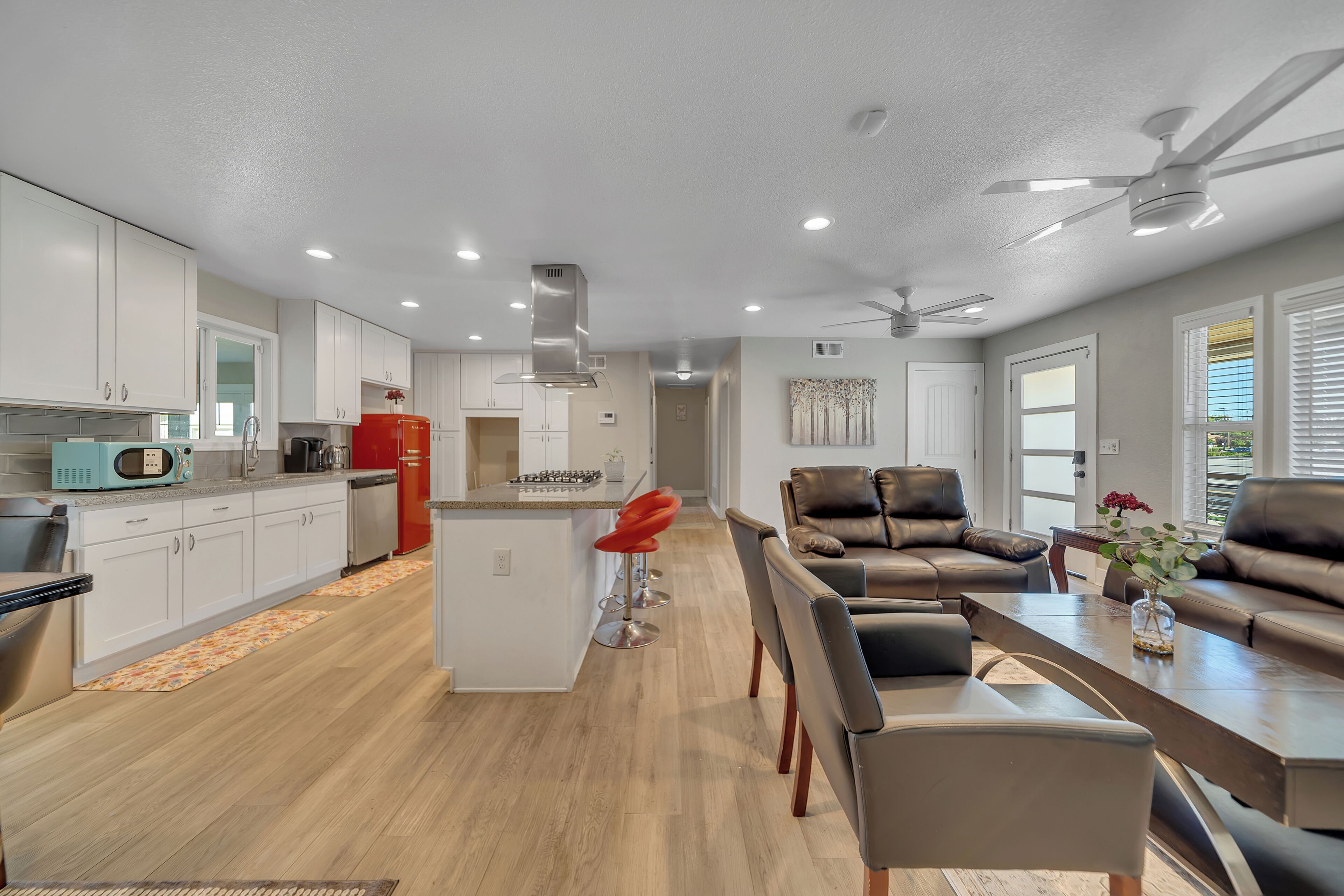 A modern kitchen with white cabinets, a red refrigerator, and a central island with a sink.