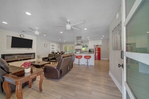 A modern living room with a flat-screen TV, leather sofa, and a dining area with a wooden table.
