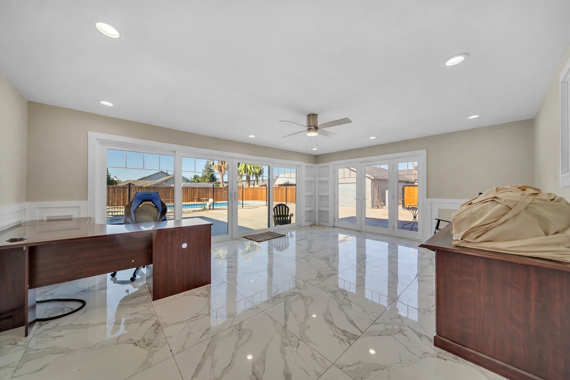 A spacious room with a marble floor, a ceiling fan, and a large sliding glass door leading to an outdoor area.