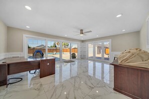 A spacious room with a marble floor, a ceiling fan, and a large sliding glass door leading to an outdoor area.