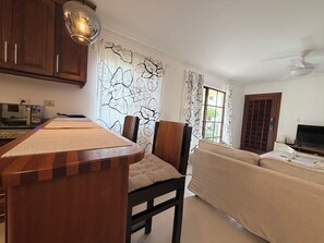 Eine moderne Küche mit Backofen, ein Essbereich mit Holztisch und Stühlen sowie ein Wohnzimmer mit Sofa und Fernseher.