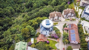 A residential area with multiple houses, some with solar panels, surrounded by dense greenery. - Hotel RF Vision Restaurante Giratorio (Gramado)