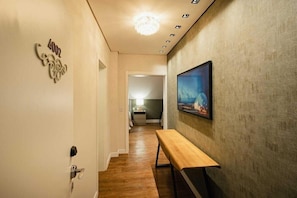 A hallway with a bench, a painting on the wall, and a door with a number plaque. - Hotel RF Vision Restaurante Giratorio (Gramado)