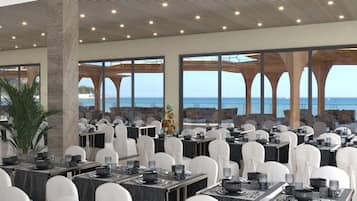 Een ruime eetruimte met gedekte tafels, grote ramen met uitzicht op zee, en een modern architectonisch ontwerp met een hoge plafond.