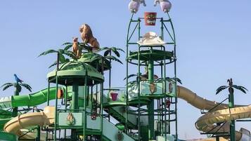 Een waterpark met een meerlaagse speelconstructie, glijbanen en een zwembad.