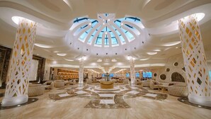 A spacious lobby with a central circular seating area, large columns with geometric patterns, and a skylight ceiling. - Sirena Beach Resort & Spa (Marsa Alam)