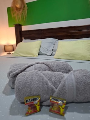 A bed with two pillows, a green wall, and two Haribo candy packages on the bed. - Tropischer Garten ,Nähe zu Stränden ,Ruhe ,gute Lage für Tamarindo (Matapalo)