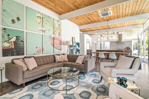A modern living room with a sectional sofa, a glass coffee table, and artwork on the walls. - No Paparazzi - Palm Springs Paradise: Your Private Poolside Retreat Awaits (Palm Springs)