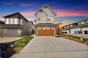 A residential neighborhood with houses, a driveway, and a basketball hoop. - Upscale Show Home | Family House | Workspace (Calgary)