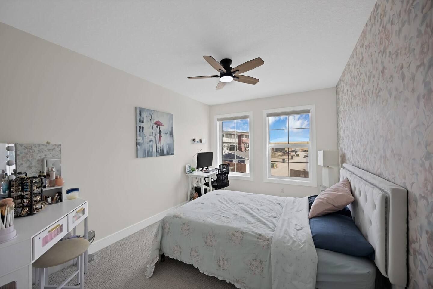 Une chambre à coucher comprenant un lit, un bureau, une chaise, un ventilateur de plafond et une fenêtre donnant sur un beau paysage.