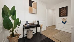 Een hal met een zwarte console tafel, een grote potplant, een schaakbord en een dromenvanger.