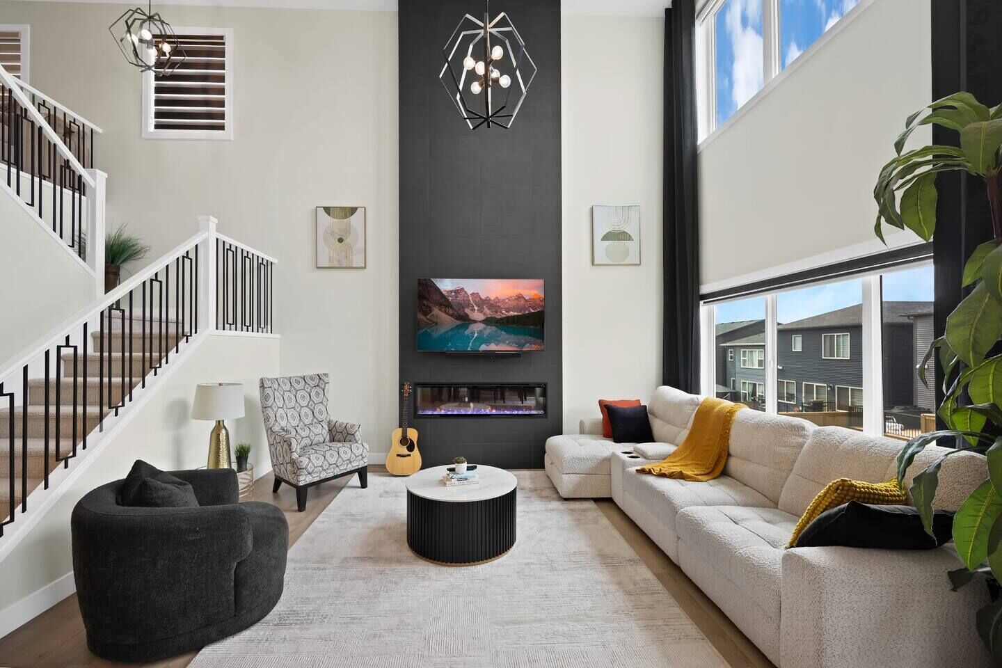 A modern living room with a staircase, a fireplace, a sofa, a coffee table, and a television.