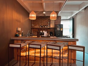 Eine Bar mit Backsteinwand, einem schwarzen Kühlschrank und einer Holztresen.