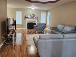 A living room with a fireplace, leather sofas, a television, and a wooden floor.