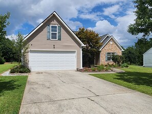 A residential house with a garage, a brick section, and a lawn.