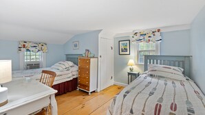 Ein Schlafzimmer mit zwei Einzelbetten, einem Schminktisch, einem Schreibtisch und einem Stuhl.