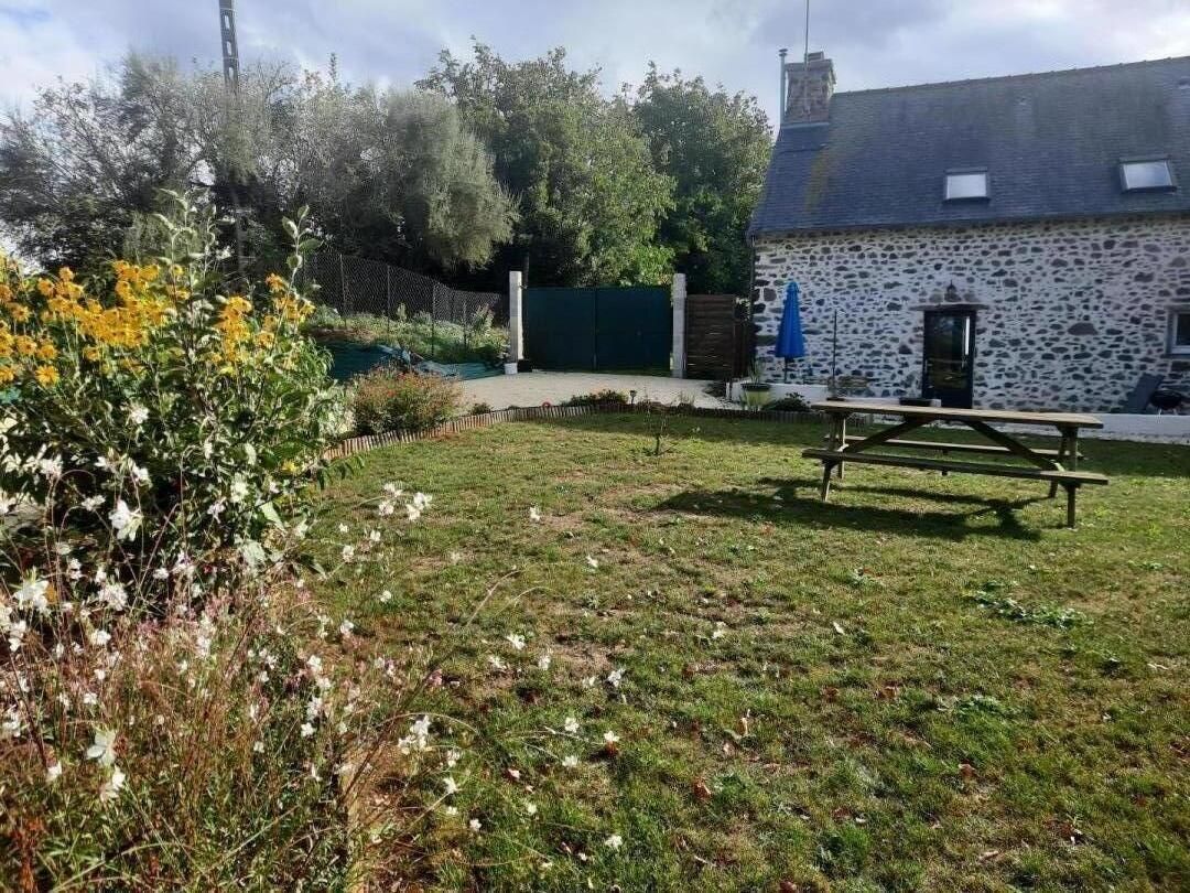 Een gebouw van steen met een omheinde tuin, een picknicktafel en een poort.