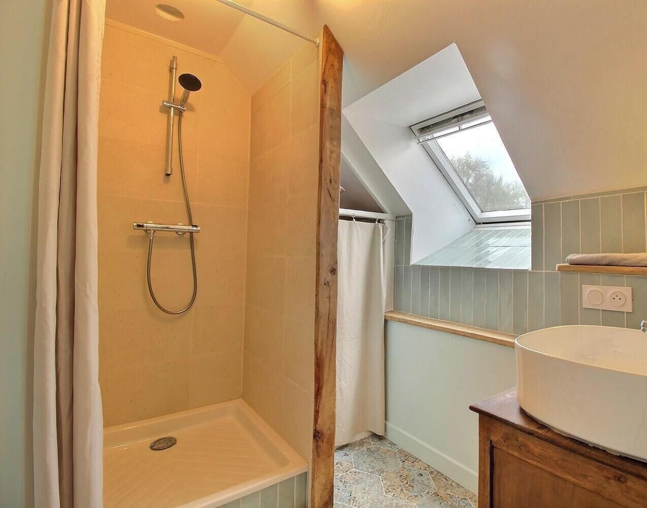Ein Badezimmer mit Dusche, Waschbecken und einem Oberlicht.
