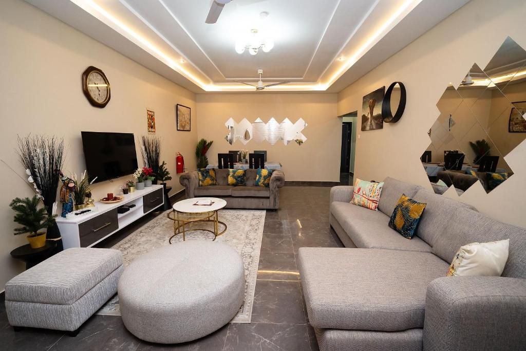 A modern living room with a grey sofa, ottoman, and a flat-screen TV.