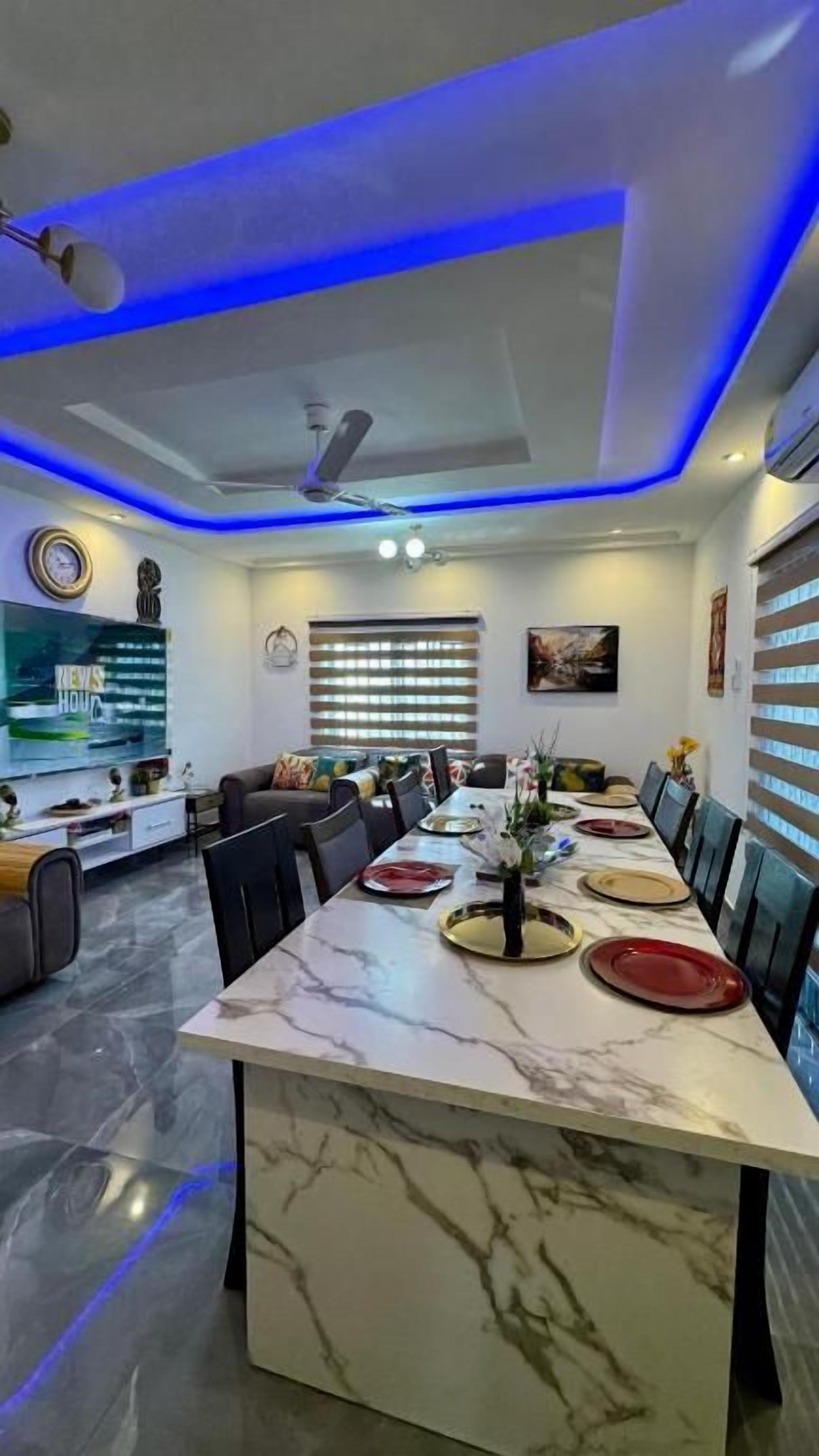 A modern dining area with a marble table, chairs, and a ceiling fan.