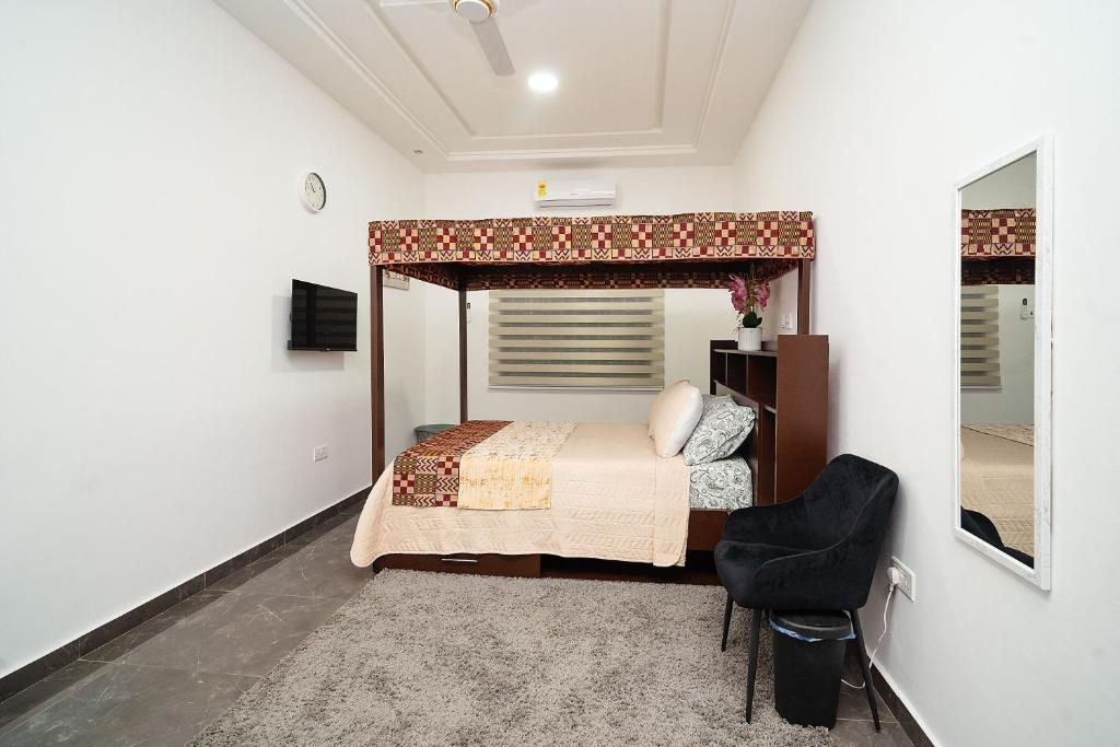 A bedroom with a bed, a chair, a mirror, and a ceiling fan.