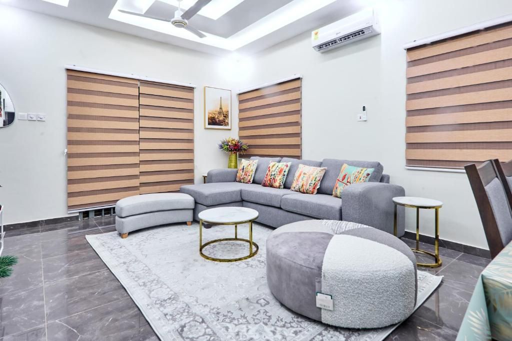 Un salon moderne avec un canapé d’angle, des poufs ronds, une table basse et un tapis à motifs.