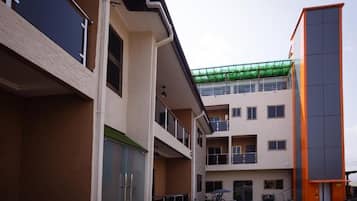 Un edificio de varios pisos con balcones, un espacio al aire libre cubierto y una estructura naranja separada.