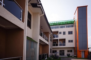 A multi-story building with balconies, a covered outdoor area, and a separate orange structure. - Cherry Signature Condos (Adenta Municipality)